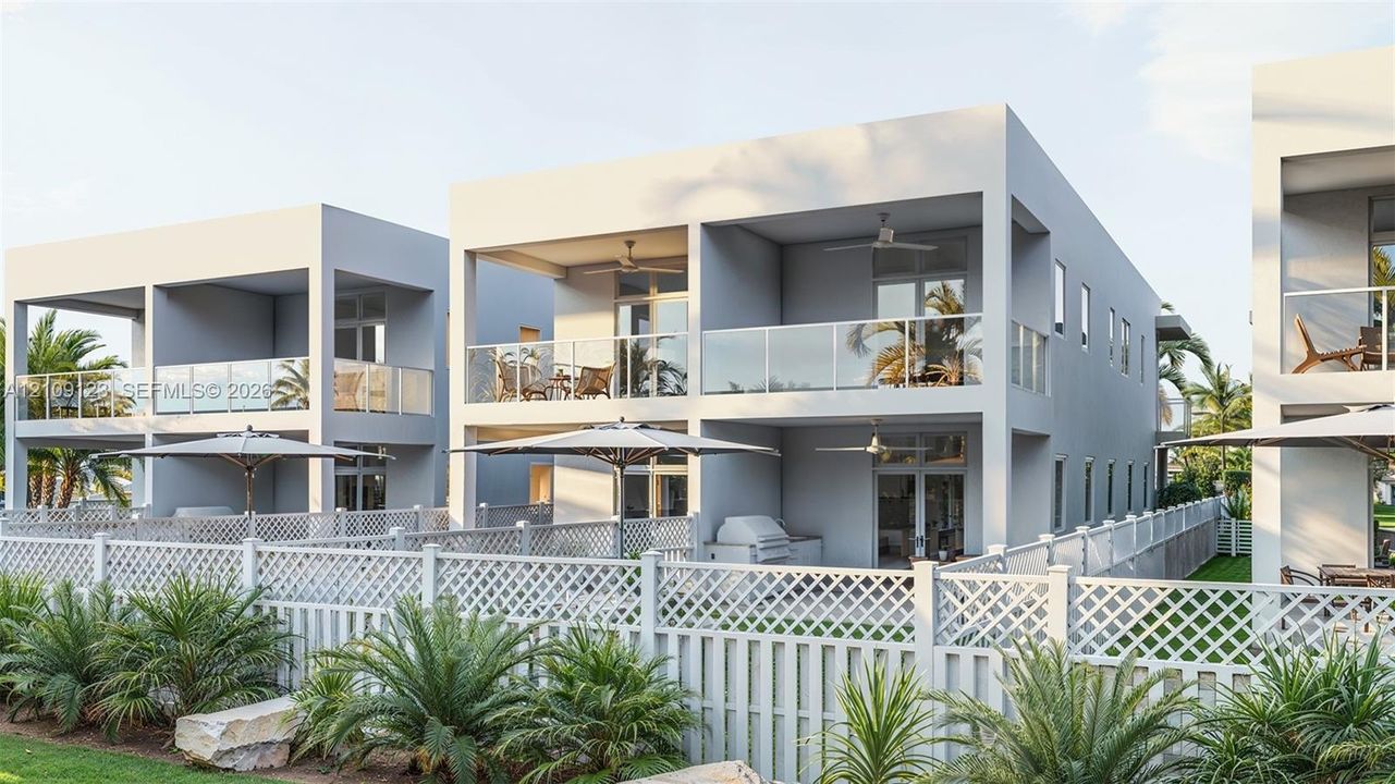 Contemporary multi-level structures featuring private covered balconies with glass railings, built-in outdoor kitchen components, and white lattice fencing