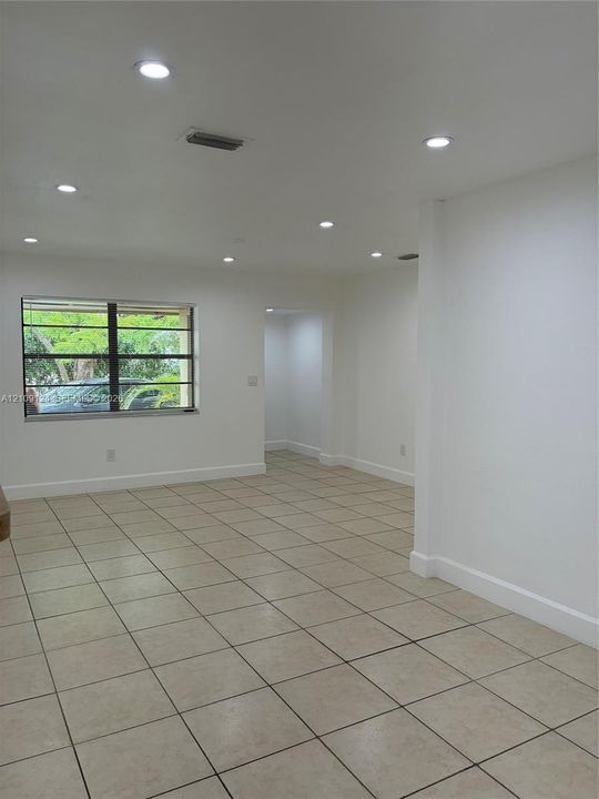 Interior area featuring neutral tile flooring, recessed lighting, and a window with dark-frame casements