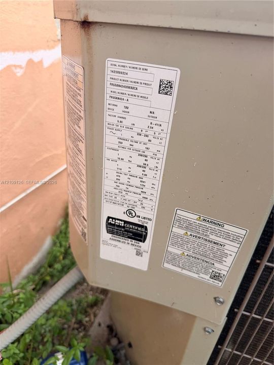 Outdoor condenser unit featuring a metal exterior casing with factory-installed identification plate and safety compliance markings