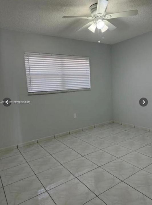 Room featuring neutral-tone ceramic tile flooring, a multi-blade ceiling fan with integrated lighting, and a single window with horizontal blinds