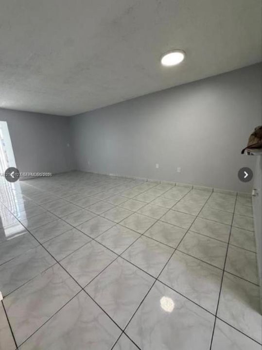 Neutral interior space featuring large-format ceramic tile flooring, neutral wall paint, and a circular flush-mount ceiling light fixture