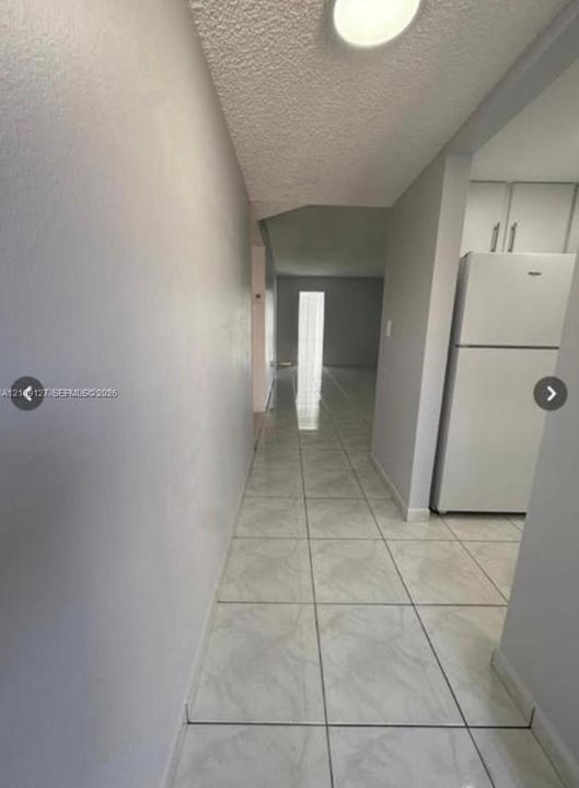 Ceramic tile flooring, white built-in cabinetry, and integrated refrigerator