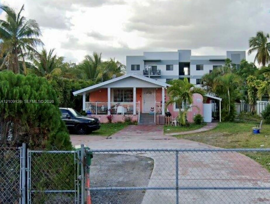 Single-story residence featuring a covered front porch, concrete driveway, and chain-link perimeter fencing