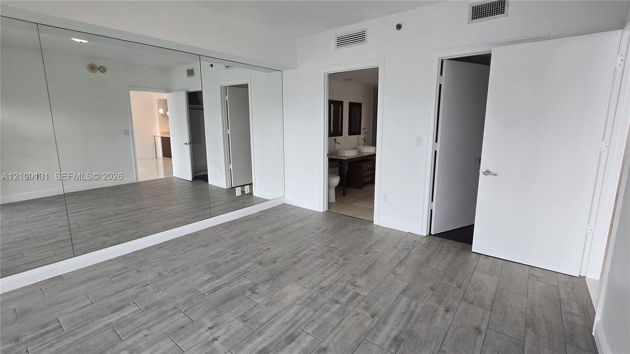 Interior space featuring floor-to-ceiling mirrored walls, wood-finish tile flooring, and multiple doorways with solid-core swing doors