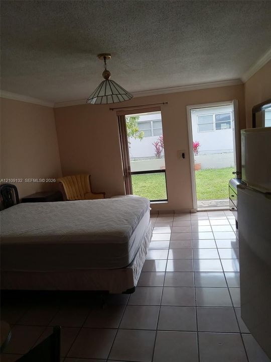 Ceramic tile flooring, crown molding, a hanging geometric pendant light, a floor-to-ceiling window, and a glass-paneled exterior door