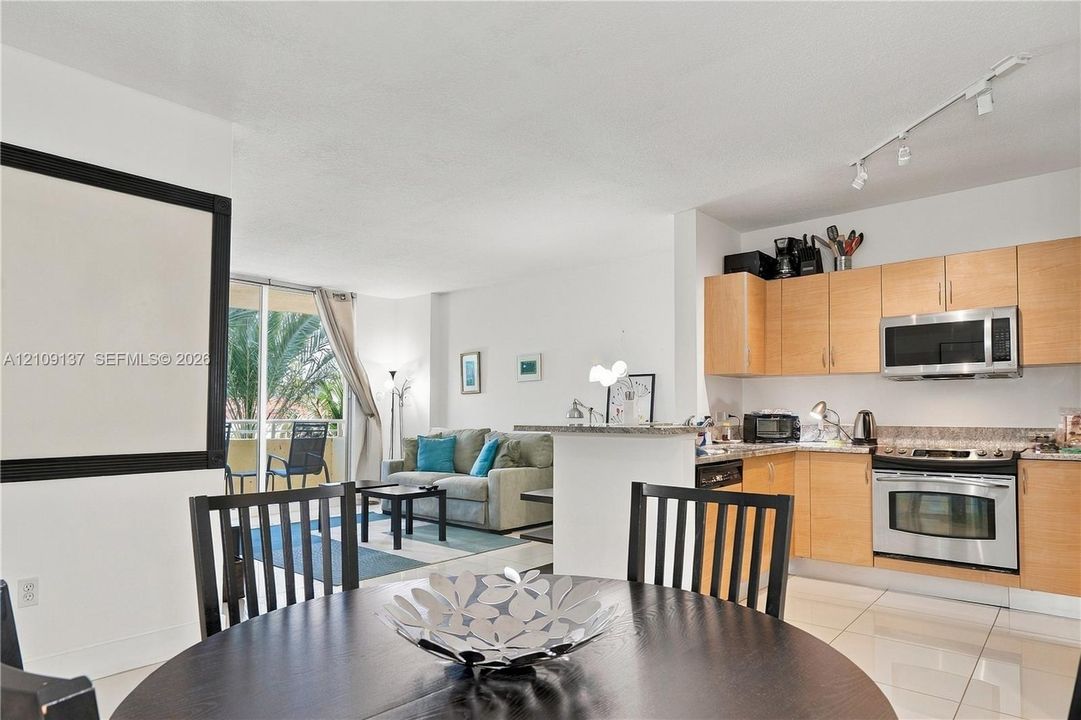 Kitchen featuring light-finish cabinetry, stone-surface countertops, and stainless steel appliances, including an over-the-range microwave and electric range