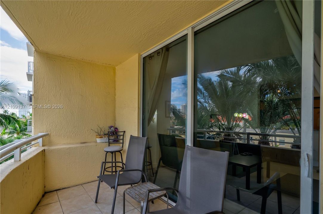 Private balcony featuring tiled flooring, textured wall surfaces, and a metal railing