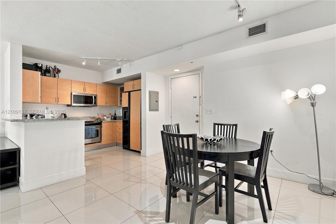 Kitchen featuring flat-panel wood cabinetry, stone countertops, stainless steel appliances, and large-format tile flooring