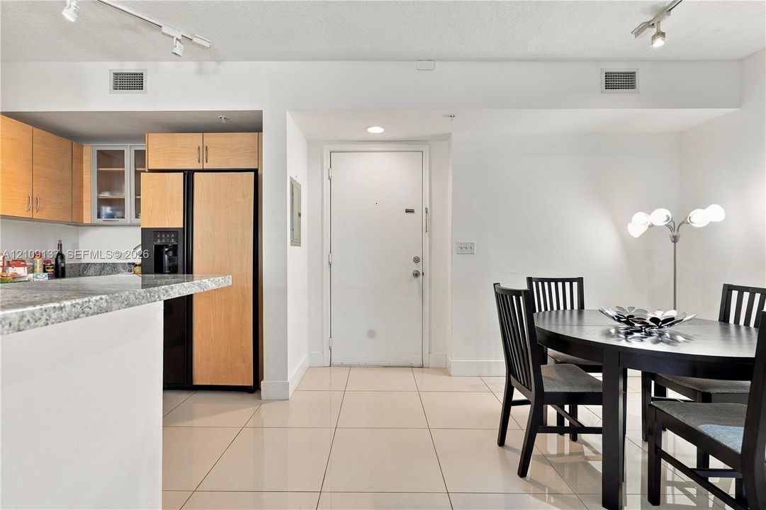 Kitchen featuring light-finish cabinetry, stone-patterned countertops, a breakfast bar, and tile flooring with track lighting