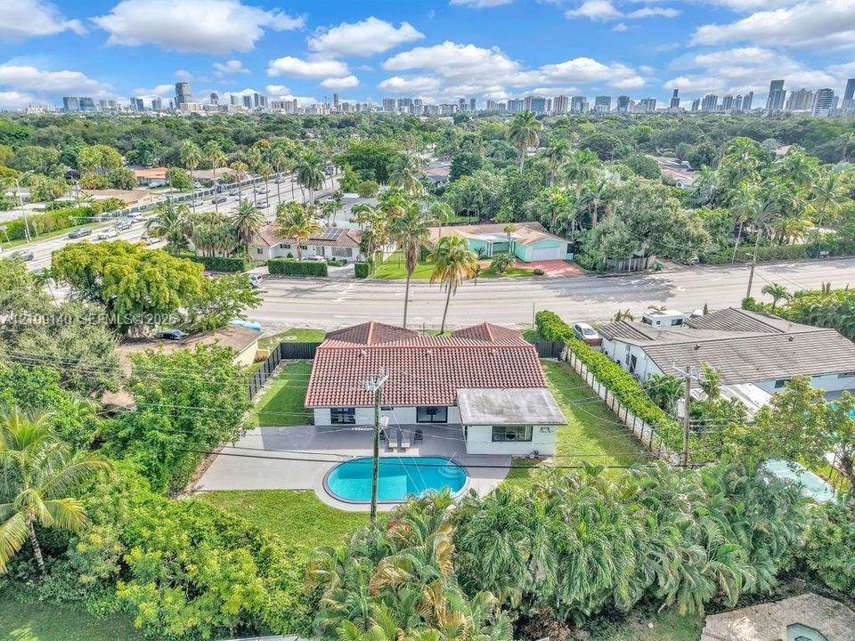 Exterior aerial perspective featuring a tile roof, an in-ground pool with a concrete patio, and mature landscaping