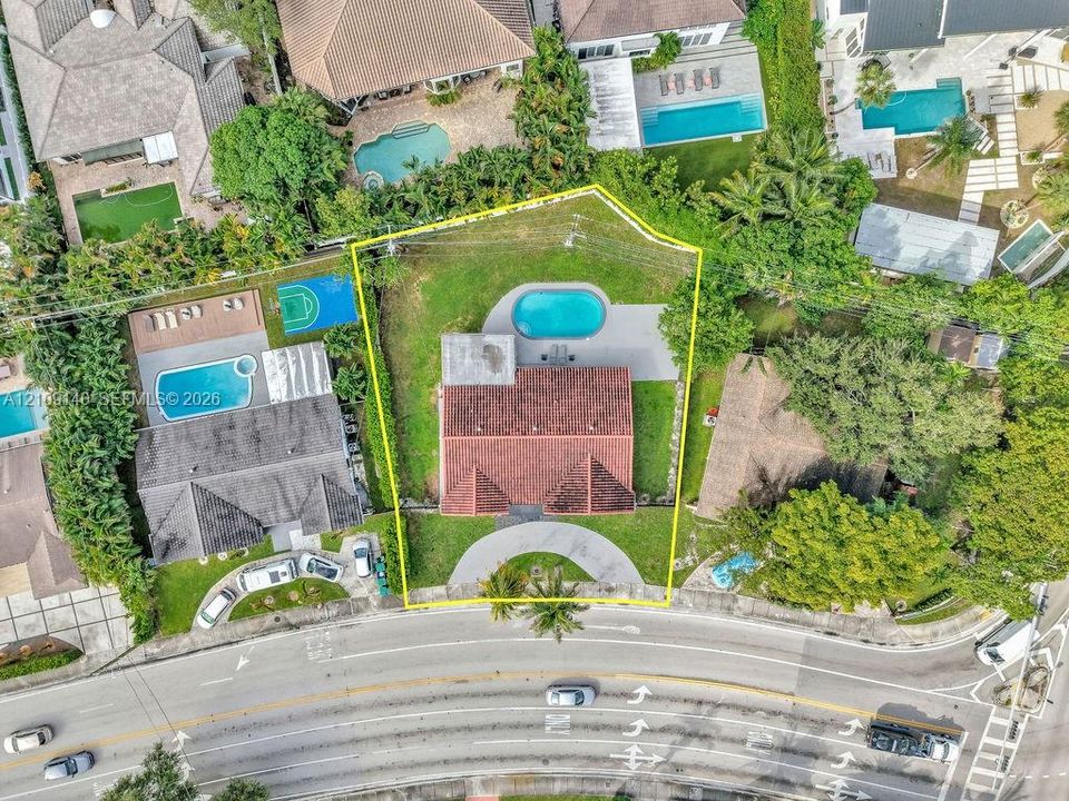 Aerial perspective featuring a multi-gabled terracotta tile roof, private swimming pool, concrete patio, expansive lawn, and a semi-circular driveway