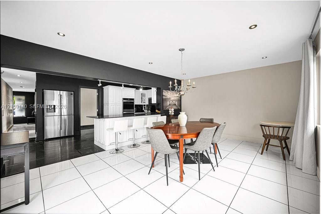 Kitchen featuring a white peninsula with a dark countertop, stainless steel refrigerator, built-in wall oven, recessed lighting, and white tile flooring