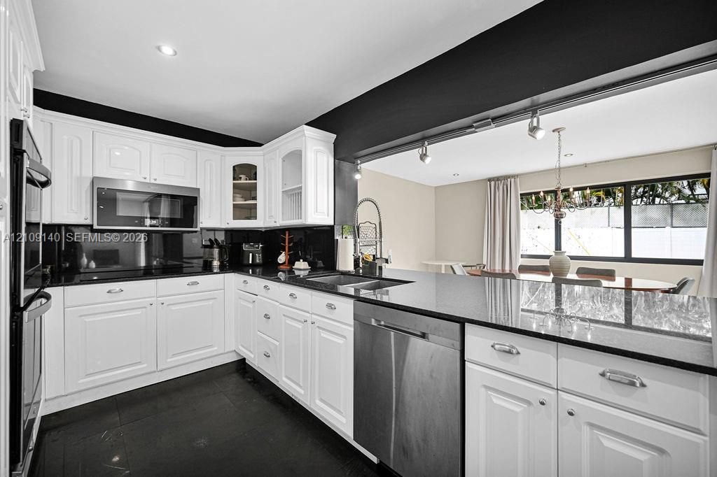 Kitchen featuring white cabinetry, dark stone countertops, stainless steel appliances, a double wall oven, and recessed lighting