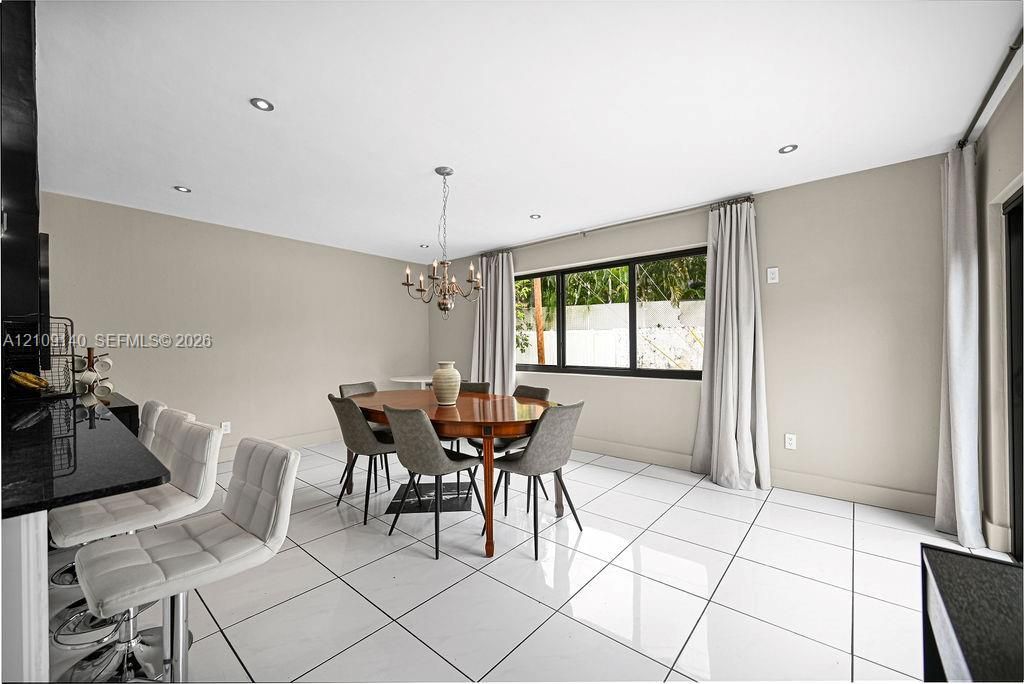 Large-format porcelain tile flooring, recessed lighting, multi-arm metal chandelier, and black-framed expansive windows