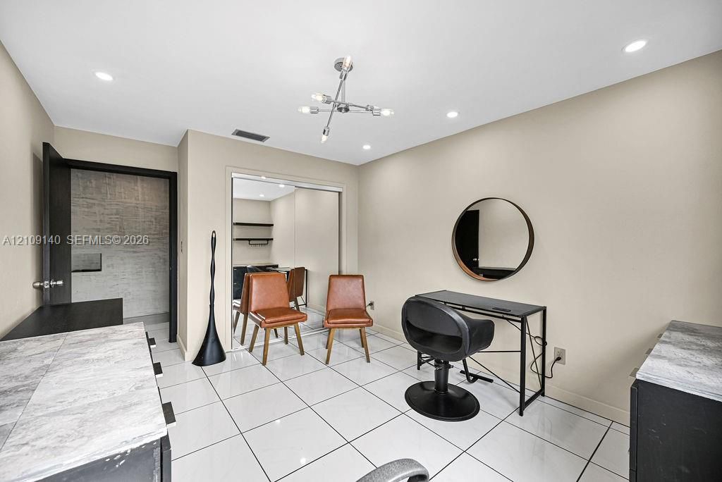 Polished tile flooring, recessed lighting, industrial-style multi-arm ceiling fixture, circular wall-mounted mirror, and sliding mirrored closet doors