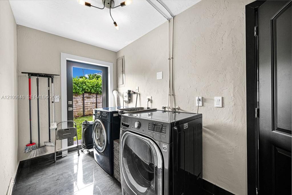 Laundry space featuring large-format tile flooring, modern multi-arm ceiling lighting, and a glass-paneled exterior door