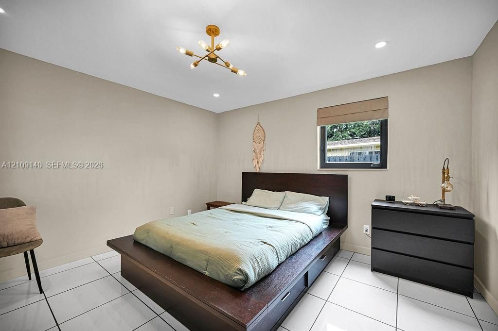 Neutral walls, polished white floor tiling, recessed lighting, and a multi-arm geometric ceiling fixture