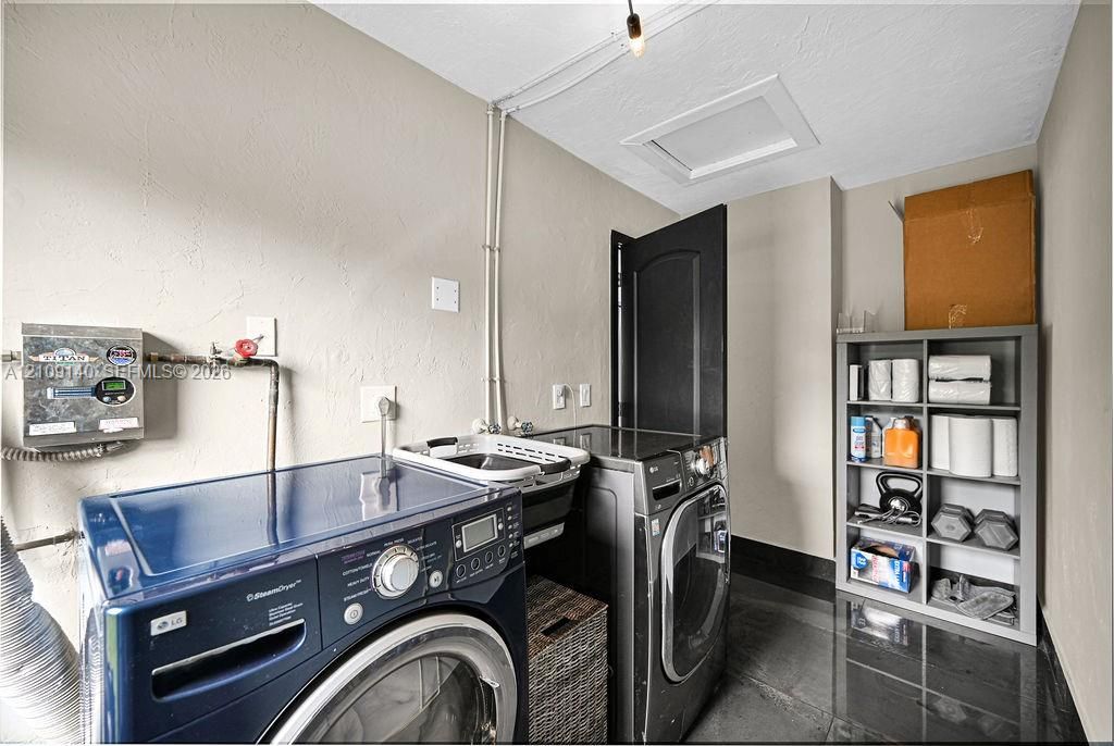 Utility room featuring dark tile flooring, neutral wall finishes, and an attic access panel