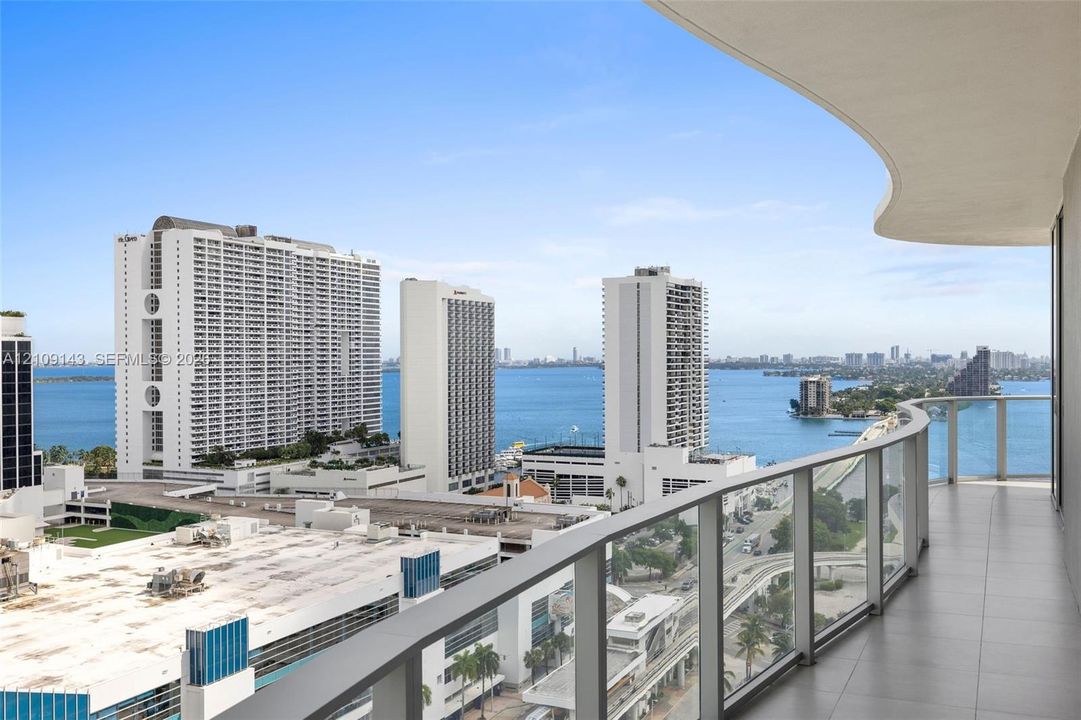 Covered balcony featuring tile flooring and a glass railing