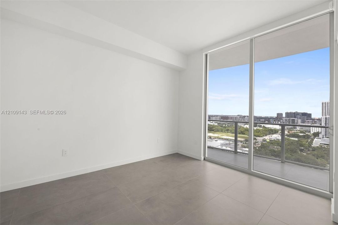 Large-format tile flooring, floor-to-ceiling windows, and balcony with metal railing