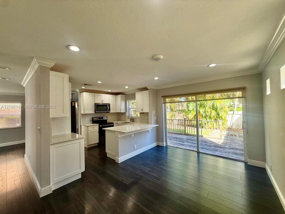 Kitchen featuring white cabinetry, solid-surface countertops, a breakfast bar, recessed lighting, and dark wood-finish flooring