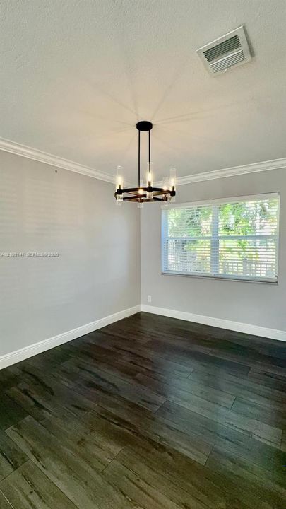 Interior space featuring wood-finish flooring, crown molding, and a multi-light chandelier with glass cylinders