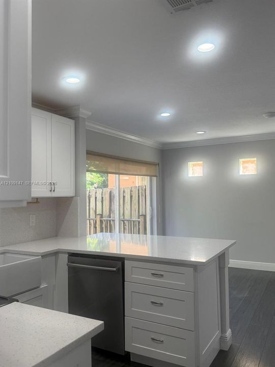 Kitchen featuring white shaker-style cabinetry, quartz countertops, stainless steel dishwasher, recessed lighting, and wood-finish flooring