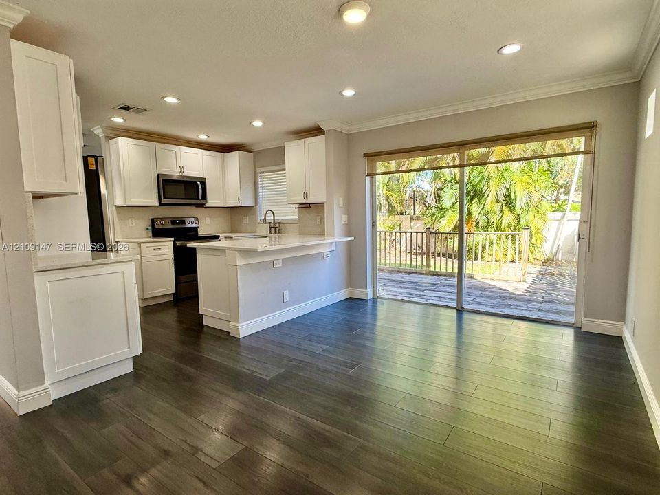 Kitchen featuring white shaker-style cabinetry, solid-surface countertops, recessed lighting, wood-finish flooring, and a sliding glass door