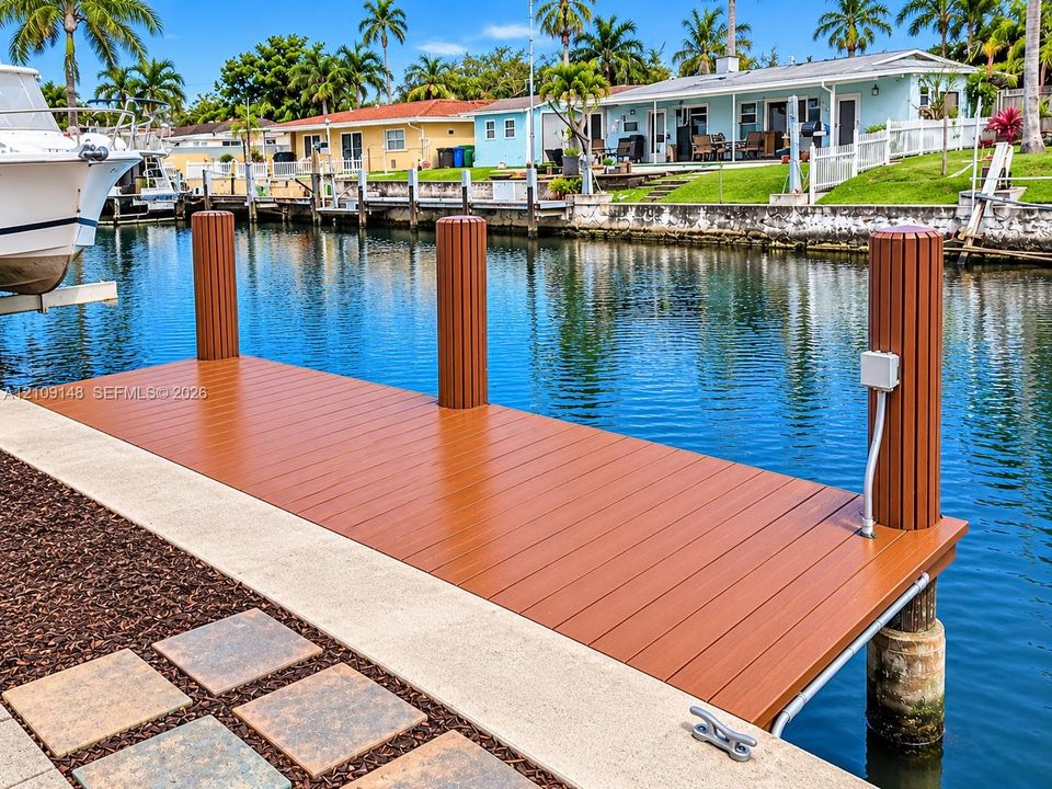 Waterfront dock featuring composite decking, vertical pilings, and a concrete bulkhead