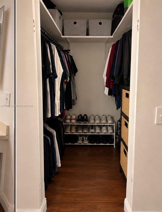 Walk-in closet featuring wood-finish flooring, dual-sided hanging rods, and overhead shelving