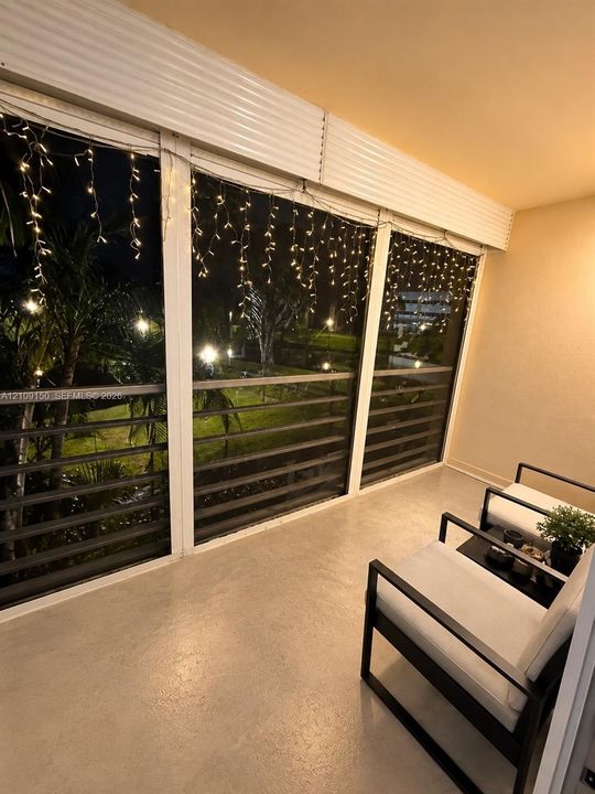 Enclosed balcony featuring floor-to-ceiling glass paneling, metal horizontal railings, and concrete flooring