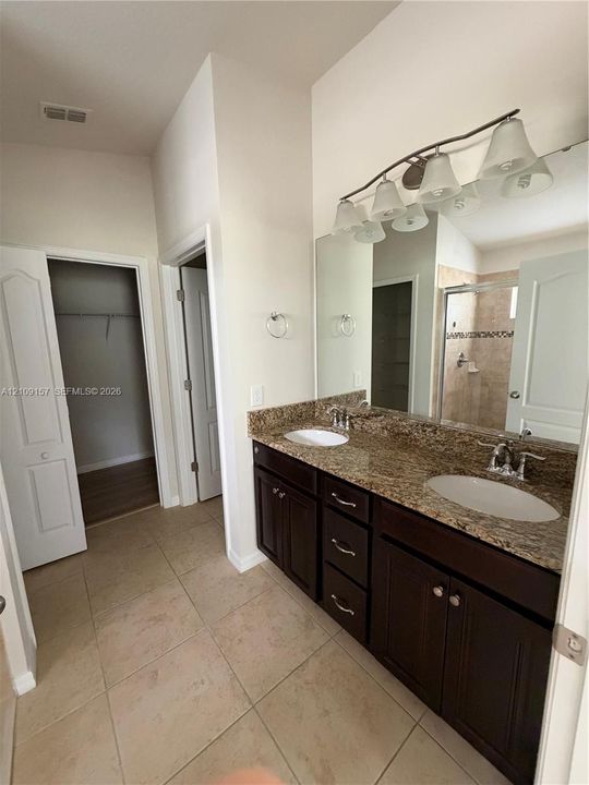 Kitchen featuring stainless steel French-door refrigerator, stone-surface countertops, cream-toned cabinetry, tile flooring, and walk-in pantry with built-in shelving