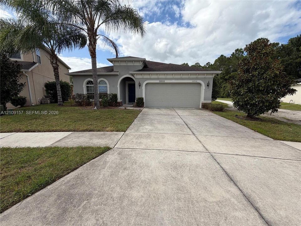 Stucco exterior featuring a hipped roof and expansive grass lawn