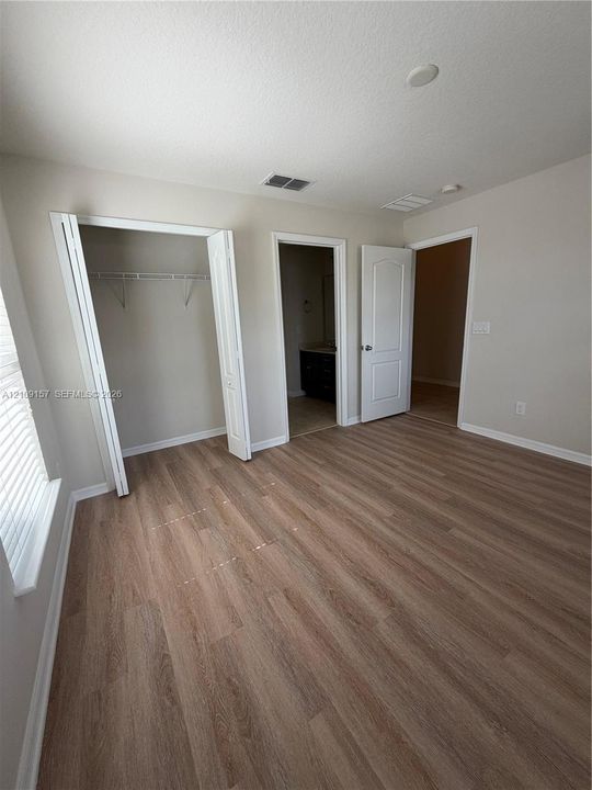 Neutral interior space featuring wood-finish flooring, vaulted ceilings, and multi-panel interior doors