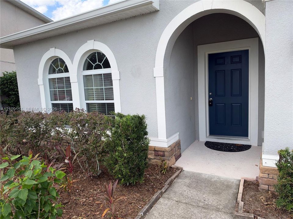 Stucco exterior featuring a covered patio, multiple single-hung windows, and a hipped roofline