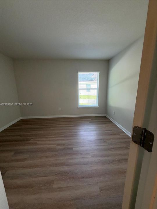 Room featuring neutral-toned walls, wood-finish flooring, and a single-pane window