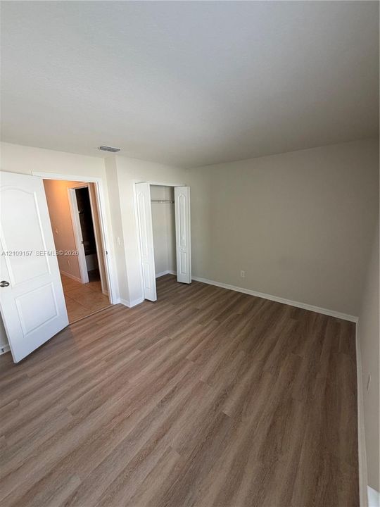 Room featuring wood-finish flooring, two arched windows, and a standard rectangular window