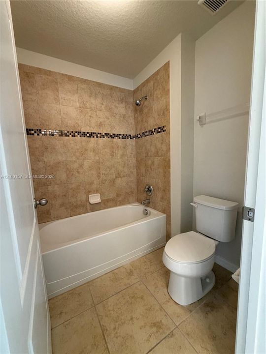 Walk-in shower featuring glass sliding doors, ceramic wall tiling with mosaic tile inlay, integrated shelving, and a horizontal window