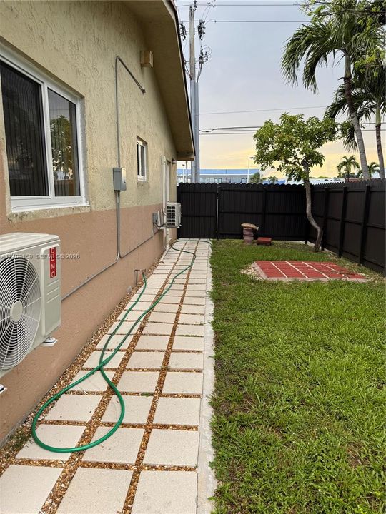 Side yard featuring a paver walkway with gravel inlay, a lawn area, and a privacy fence