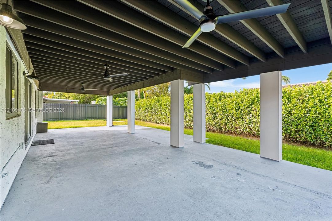Covered outdoor patio featuring a concrete floor, exposed beam ceiling, built-in ceiling fans, and structural support columns