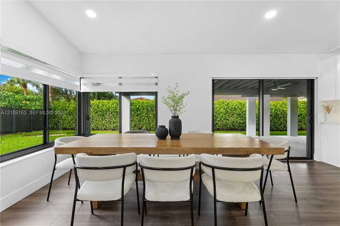 Open-concept interior featuring wood-finish flooring, recessed lighting, and extensive floor-to-ceiling glass paneling with integrated sliding doors