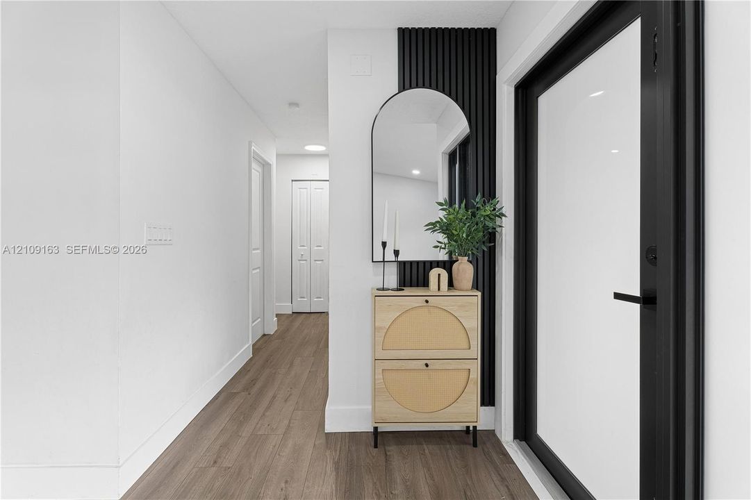 Entryway featuring wood-finish flooring, a matte black door frame, and a vertical slat accent wall