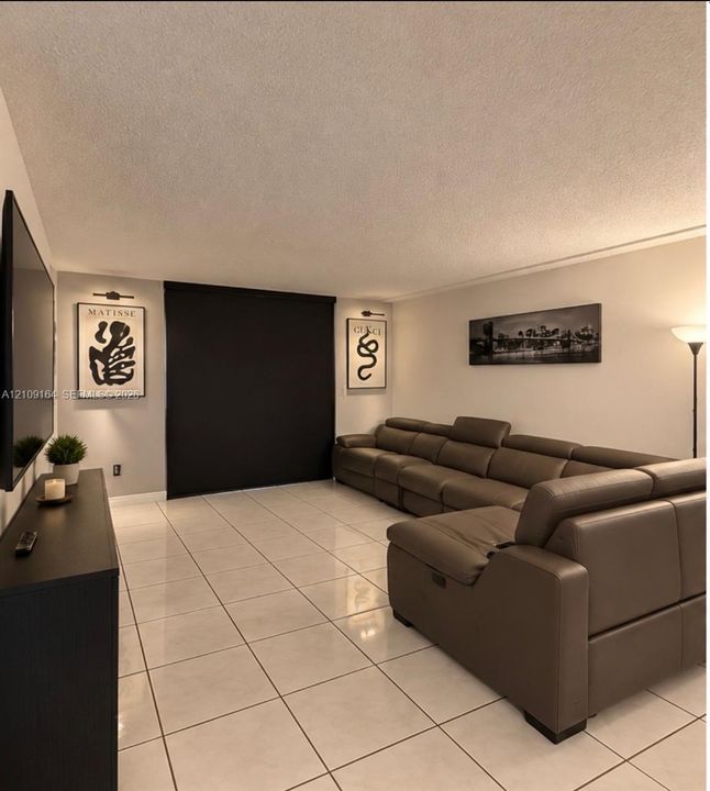 Large-format square floor tiles, wall-mounted picture lighting, and opaque window shades