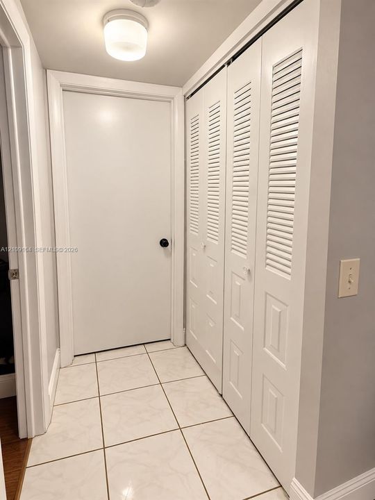 Tiled flooring, dual louvered-panel closet doors, and a ceiling-mounted light fixture
