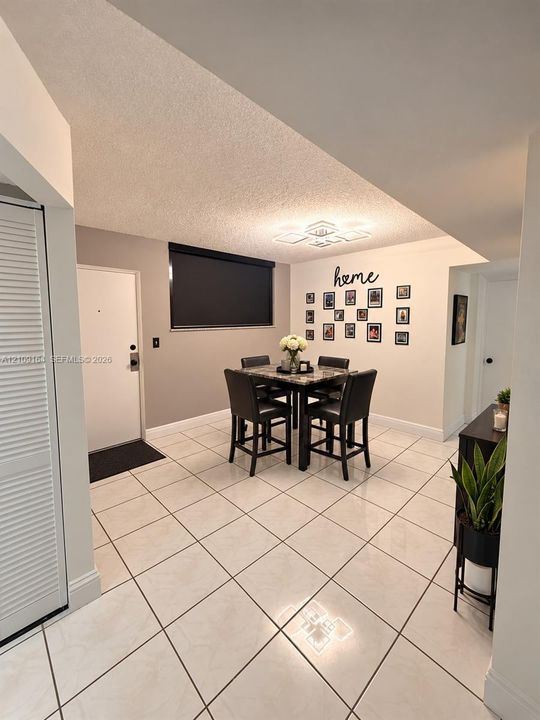 Interior area featuring large-format ceramic tile flooring, a geometric flush-mount light fixture, and a neutral wall palette