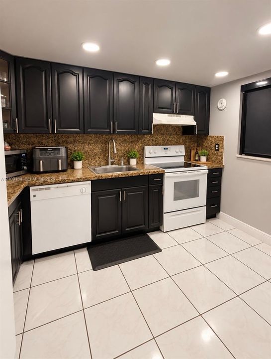 Kitchen featuring dark cabinetry, stone-surface countertops, tile flooring, recessed lighting, and a stainless steel undermount sink