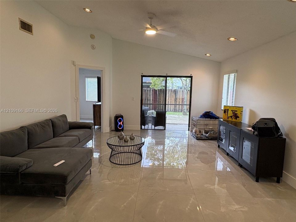 Large-format tile flooring, vaulted ceilings, recessed lighting, ceiling fan, and sliding glass doors