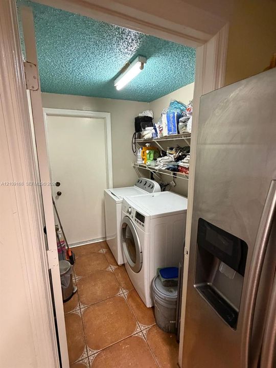 Utility space featuring tiled flooring, built-in wire shelving, and an exterior door
