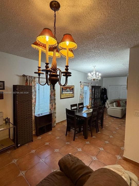 Tiled flooring with decorative geometric inlays, multi-tiered chandelier with tasseled shades, and secondary crystal-style overhead lighting