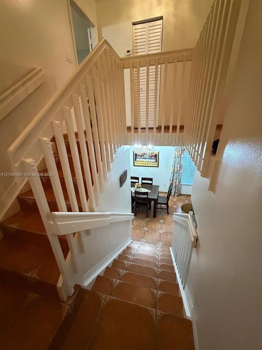 Staircase featuring white balustrades and handrails, complemented by terra cotta tile flooring